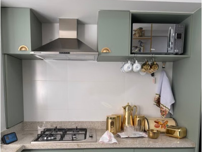 Cozinha com armários em verde-sálvia e puxadores dourados