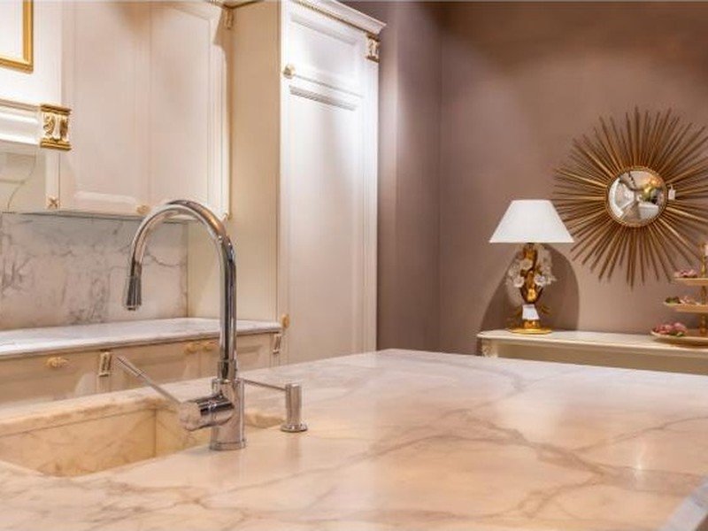 Bancada de mármore com torneira e detalhes dourados em cozinha clássica