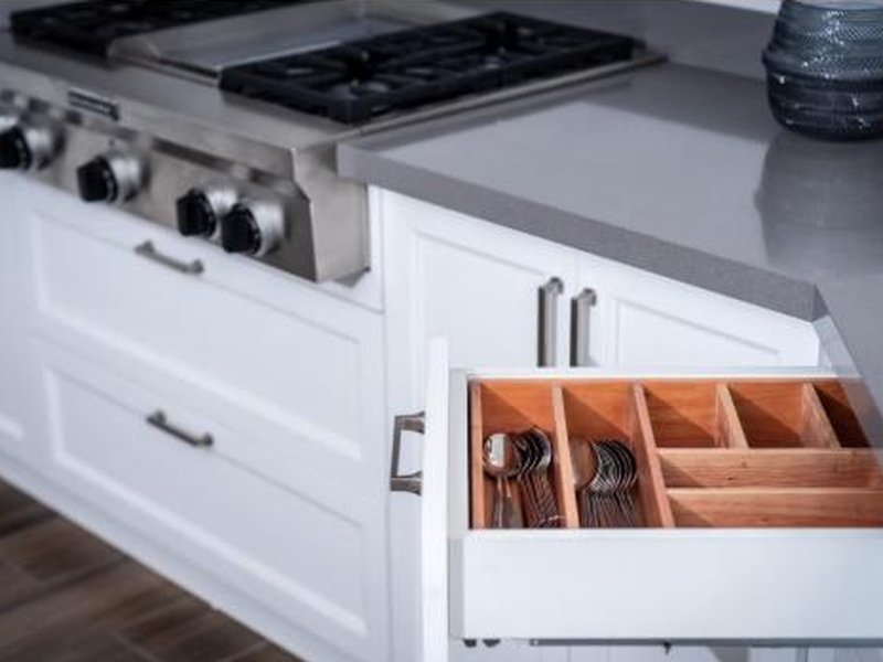 Gaveta de cozinha com divisórias de madeira organizando talheres