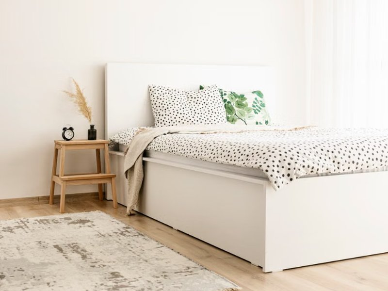Tapete claro posicionado parcialmente embaixo da cama em quarto minimalista