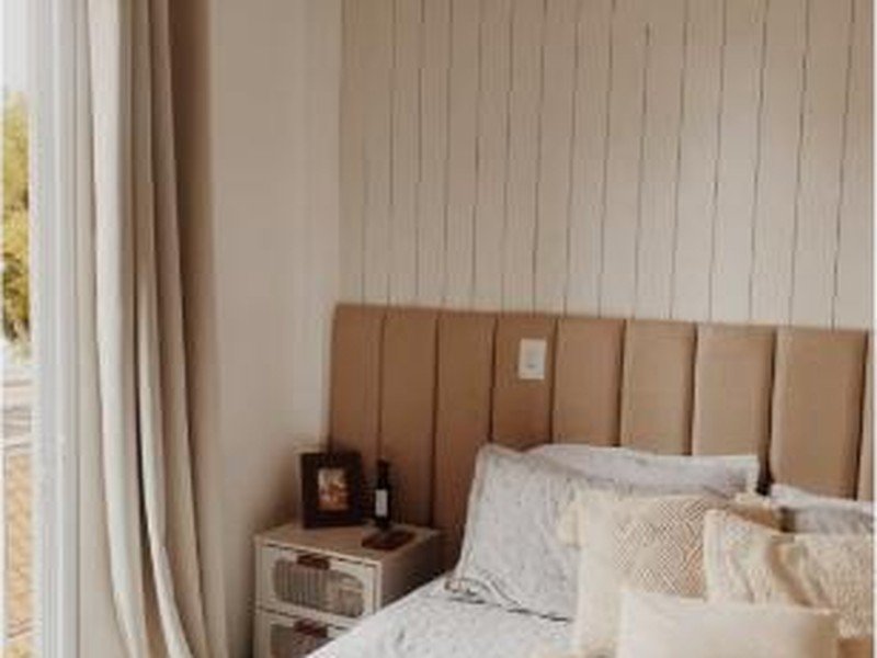 Quarto em tons neutros bege com cabeceira estofada e parede ripada