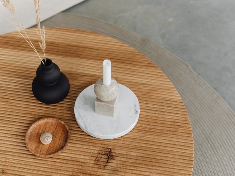 Tampo de mesa de centro de madeira com vaso preto, castiçal de mármore e objeto decorativo em madeira