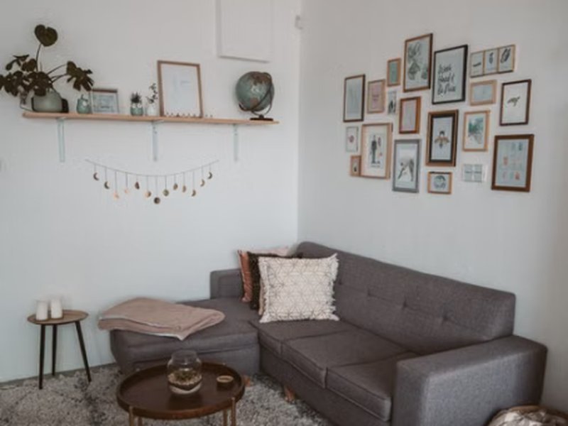 Sofá de canto cinza compacto em sala de estar pequena com quadros na parede